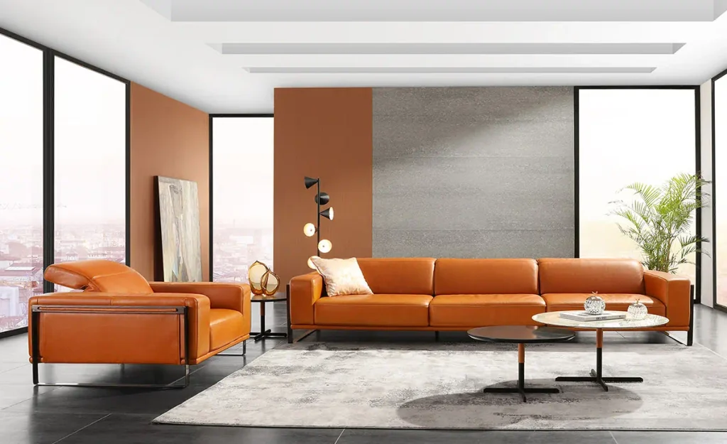 Divano Bamboo in pelle arancione moderno, design elegante, con tavolino in vetro e pareti color terracotta. Arredamento contemporaneo.