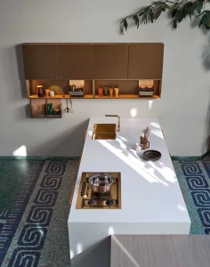 Cucina Cesar MAXIMA 2.2 STYLISH FLARE moderna con isola bianca, armadietti marroni, dettagli dorati e pavimento decorato.